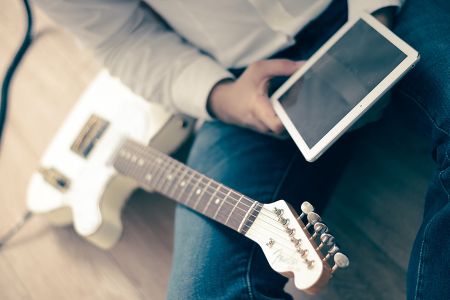 玩吉他的人坐在地板上双手拿着iPad高清场景样机素材